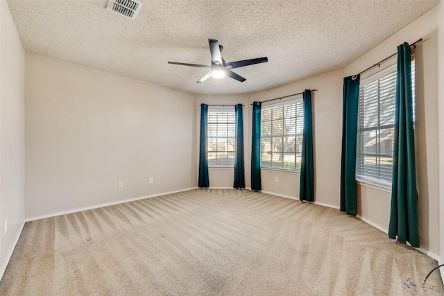 unfurnished room with a textured ceiling, light colored carpet, and ceiling fan