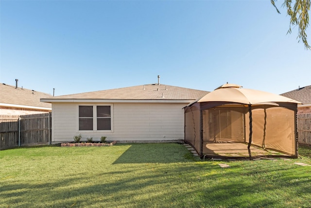 rear view of house featuring a gazebo and a yard