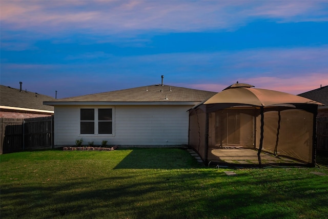 back house at dusk with a lawn