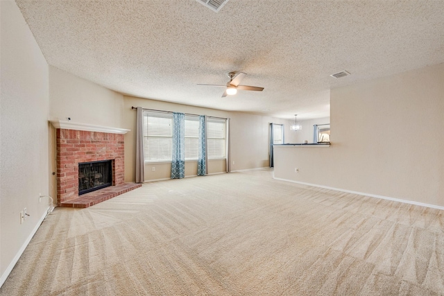 unfurnished living room featuring a textured ceiling, ceiling fan, light carpet, and a brick fireplace