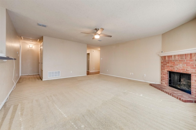 unfurnished living room featuring ceiling fan, light colored carpet, a textured ceiling, and a brick fireplace