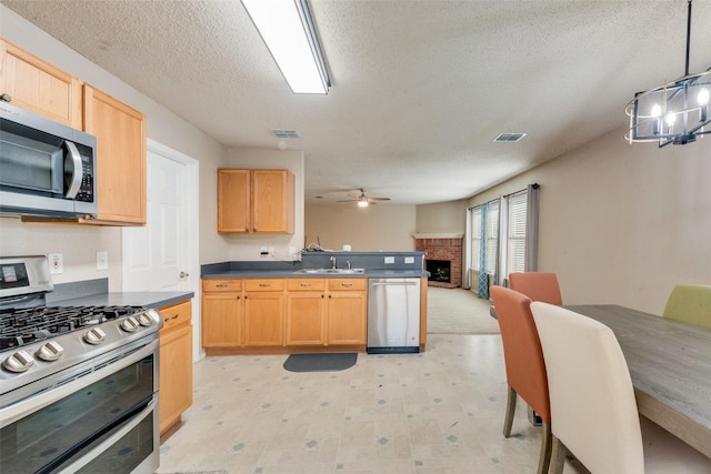 kitchen featuring appliances with stainless steel finishes, a textured ceiling, ceiling fan, sink, and decorative light fixtures