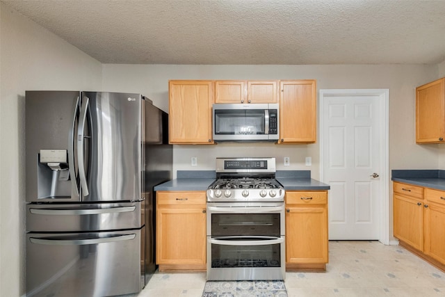 kitchen featuring light brown cabinetry, stainless steel appliances, and a textured ceiling