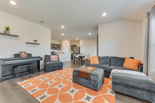 living room featuring vaulted ceiling, wood finished floors, visible vents, and recessed lighting