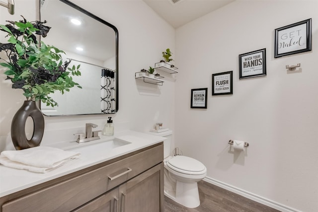 bathroom with baseboards, a shower with shower curtain, toilet, wood finished floors, and vanity