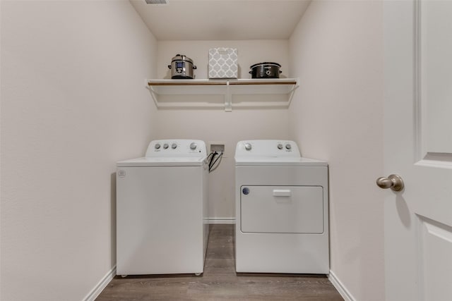 laundry area featuring laundry area, baseboards, wood finished floors, and washing machine and clothes dryer