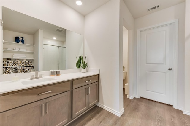 bathroom featuring visible vents, vanity, baseboards, and wood finished floors