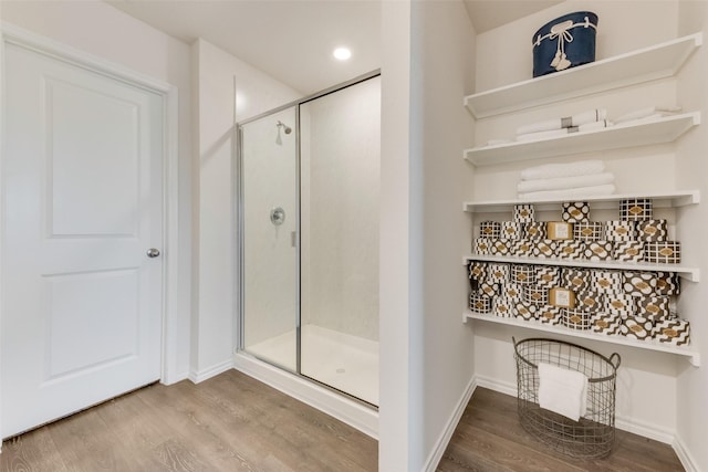 bathroom featuring a stall shower, baseboards, and wood finished floors