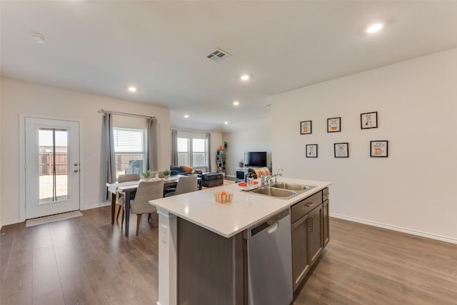 kitchen with a center island with sink, light countertops, open floor plan, a sink, and dishwasher