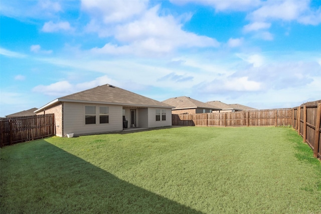 rear view of property with a fenced backyard, a lawn, and brick siding