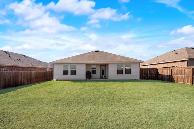 back of house with a fenced backyard and a yard