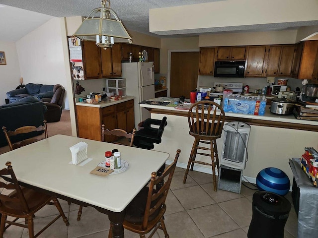 kitchen featuring light tile patterned flooring, white appliances, hanging light fixtures, and a textured ceiling