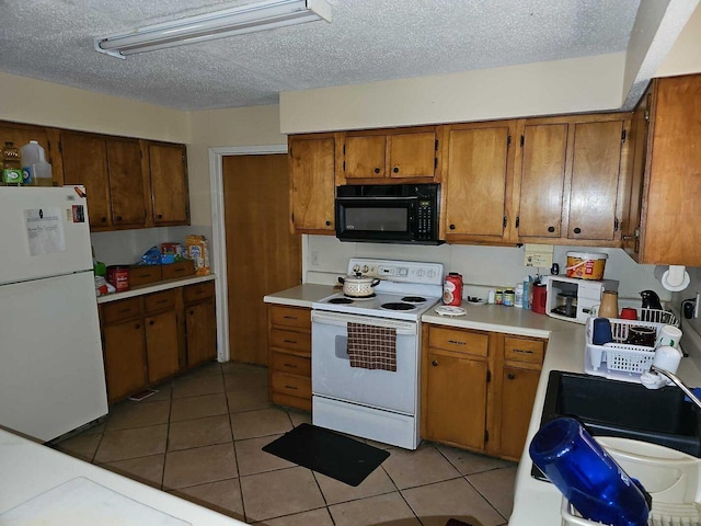 kitchen featuring a textured ceiling, light tile patterned flooring, and white appliances