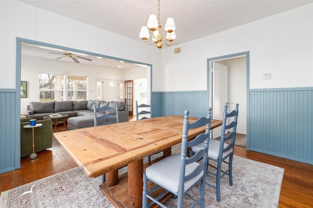 dining area featuring a textured ceiling, ceiling fan with notable chandelier, and dark wood-type flooring