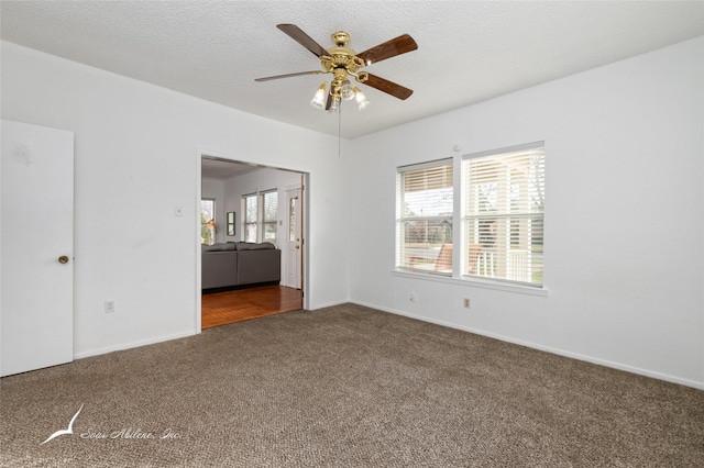 carpeted empty room with ceiling fan, a healthy amount of sunlight, and a textured ceiling