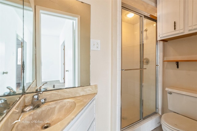 bathroom featuring vanity, toilet, and a shower with shower door