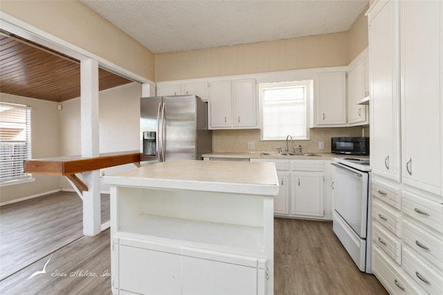 kitchen with stainless steel refrigerator with ice dispenser, electric stove, sink, white cabinets, and a kitchen island