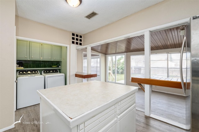 kitchen with hardwood / wood-style flooring, washer and dryer, a textured ceiling, and green cabinetry