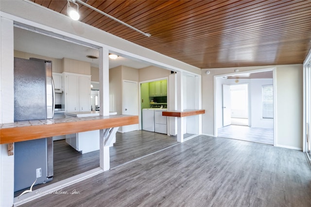 kitchen featuring washer and dryer, white cabinetry, stainless steel fridge, a breakfast bar, and wood ceiling