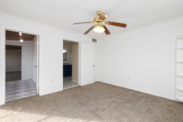 unfurnished bedroom featuring light carpet, ensuite bath, ornamental molding, a textured ceiling, and ceiling fan