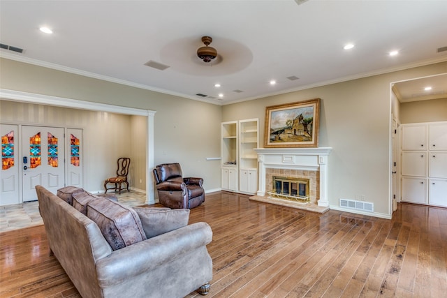 living room with wood-type flooring, ornamental molding, and ceiling fan