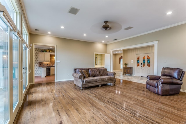 living room featuring crown molding, ceiling fan, and light wood-type flooring