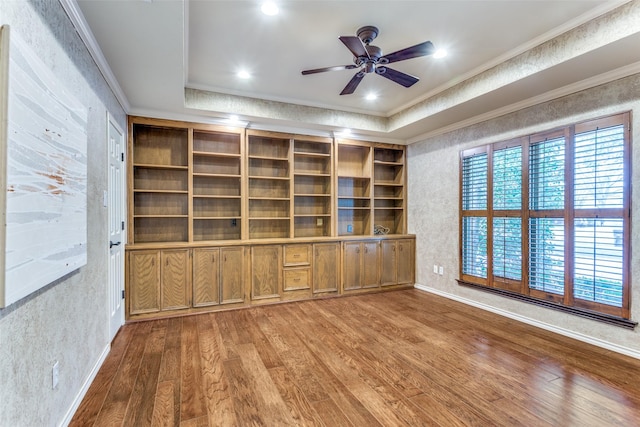 unfurnished living room featuring crown molding, wood-type flooring, a raised ceiling, and ceiling fan