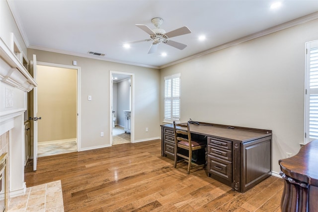 office area featuring hardwood / wood-style floors, crown molding, a tile fireplace, and ceiling fan