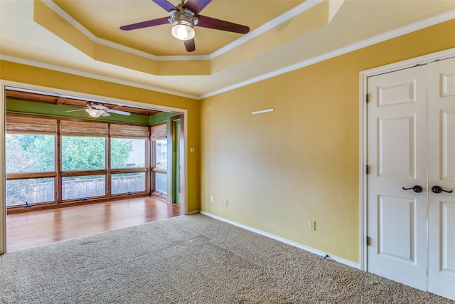 unfurnished room with a tray ceiling, ornamental molding, ceiling fan, and carpet flooring