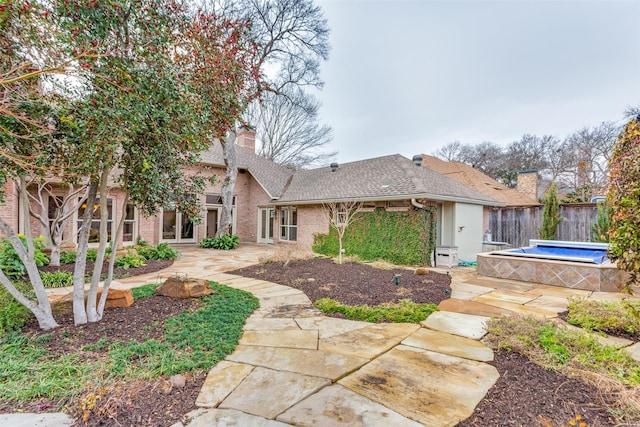 back of house with a jacuzzi and a patio area