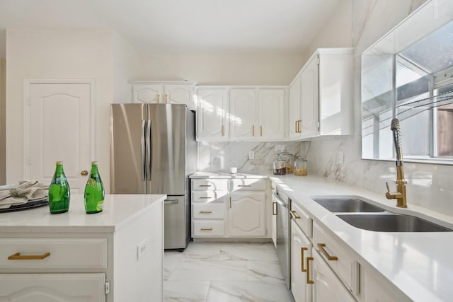 kitchen featuring tasteful backsplash, white cabinets, sink, and stainless steel appliances