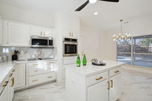 kitchen featuring decorative light fixtures, backsplash, stainless steel appliances, white cabinets, and ceiling fan with notable chandelier