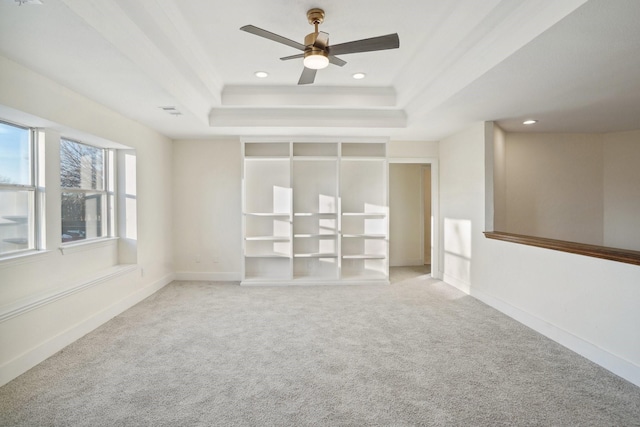 unfurnished room with ceiling fan, light colored carpet, and a raised ceiling