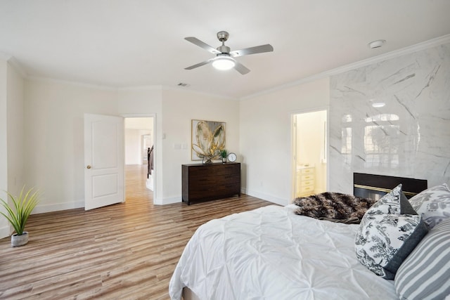 bedroom with ensuite bath, a premium fireplace, ornamental molding, light wood-type flooring, and ceiling fan