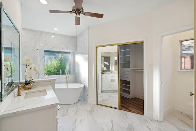 bathroom with a bathing tub, vanity, and ceiling fan