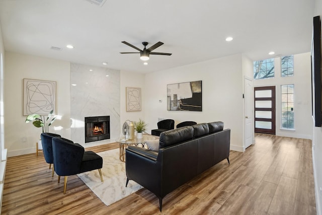 living room featuring ceiling fan, a fireplace, and light hardwood / wood-style flooring