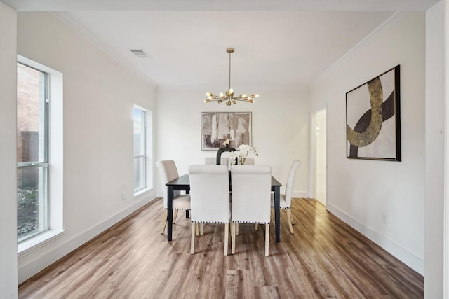 dining space featuring crown molding, hardwood / wood-style floors, and a notable chandelier