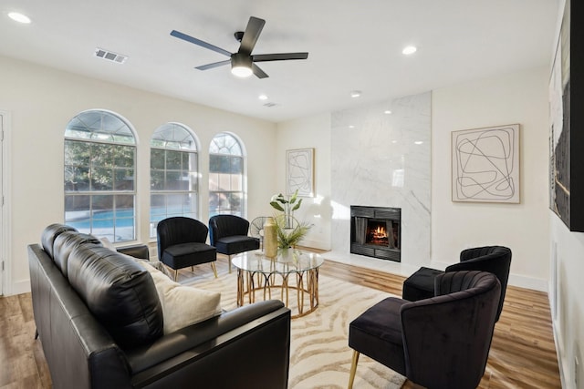 living room featuring ceiling fan, a fireplace, and light hardwood / wood-style flooring