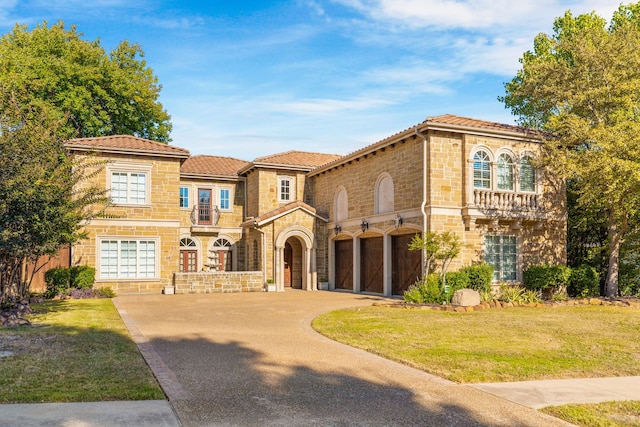 mediterranean / spanish home featuring a garage and a front lawn