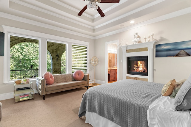 carpeted bedroom with ensuite bathroom, ceiling fan, a raised ceiling, and crown molding