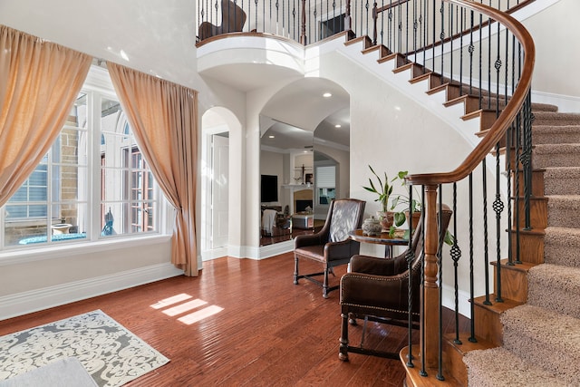 entryway featuring a towering ceiling, wood-type flooring, and ornamental molding