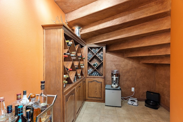 wine room featuring beamed ceiling and light tile patterned floors