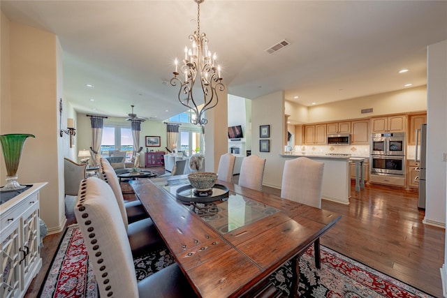 dining area featuring dark wood-type flooring and ceiling fan with notable chandelier