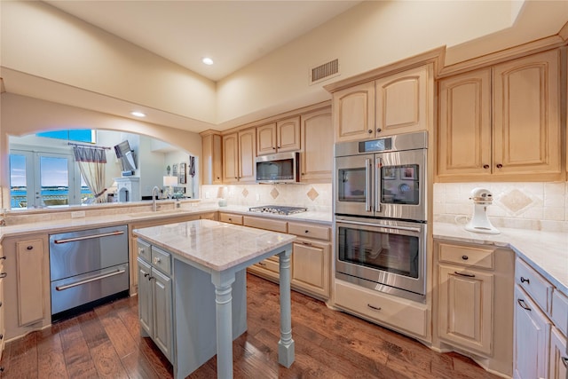 kitchen with a kitchen island, appliances with stainless steel finishes, sink, backsplash, and dark hardwood / wood-style flooring