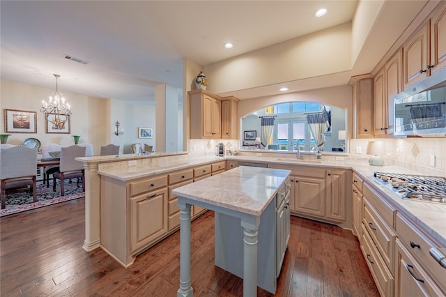 kitchen with a notable chandelier, a kitchen island, a breakfast bar, sink, and stainless steel appliances