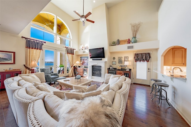 living room with ceiling fan, french doors, dark hardwood / wood-style floors, and a high ceiling