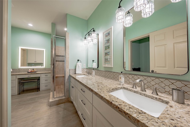 bathroom featuring an enclosed shower, vanity, decorative backsplash, a notable chandelier, and hardwood / wood-style flooring