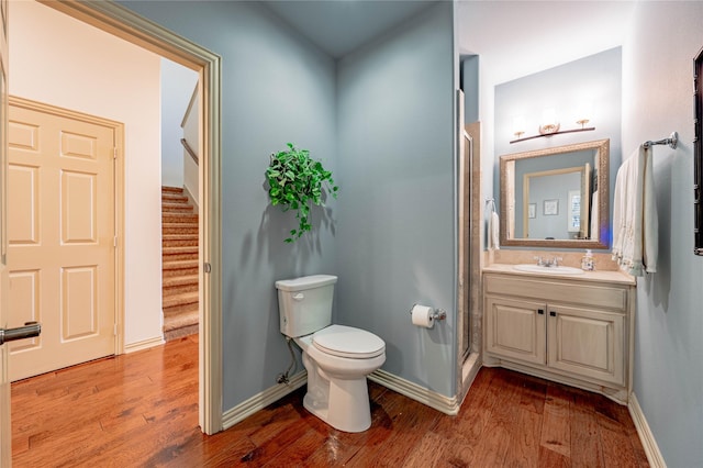 bathroom with a shower with shower door, hardwood / wood-style floors, toilet, and vanity