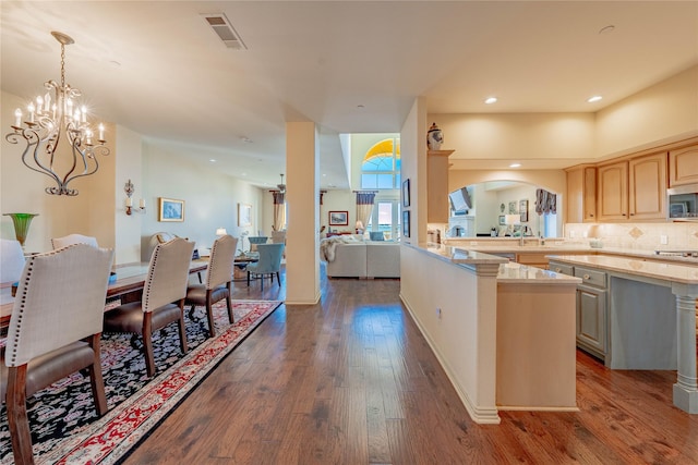 kitchen featuring dark wood-type flooring, light brown cabinets, backsplash, hanging light fixtures, and a chandelier