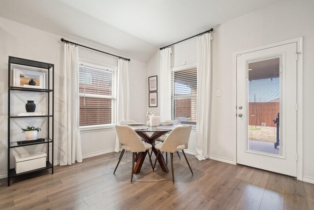 dining area with hardwood / wood-style floors and vaulted ceiling